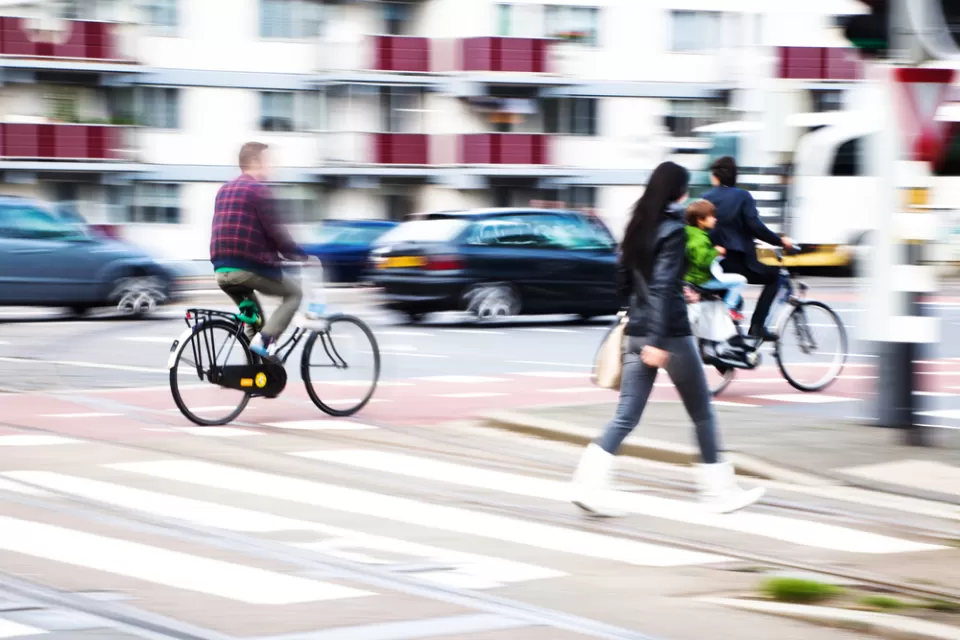 Pedestrians and cyclists in busy city crosswalk with blurred motion
